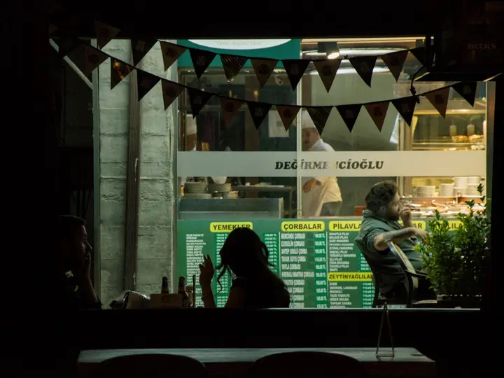 Silueta de una persona frente al escaparate iluminado de una tienda de noche