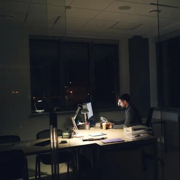 Persona trabajando de noche en un escritorio con luz tenue