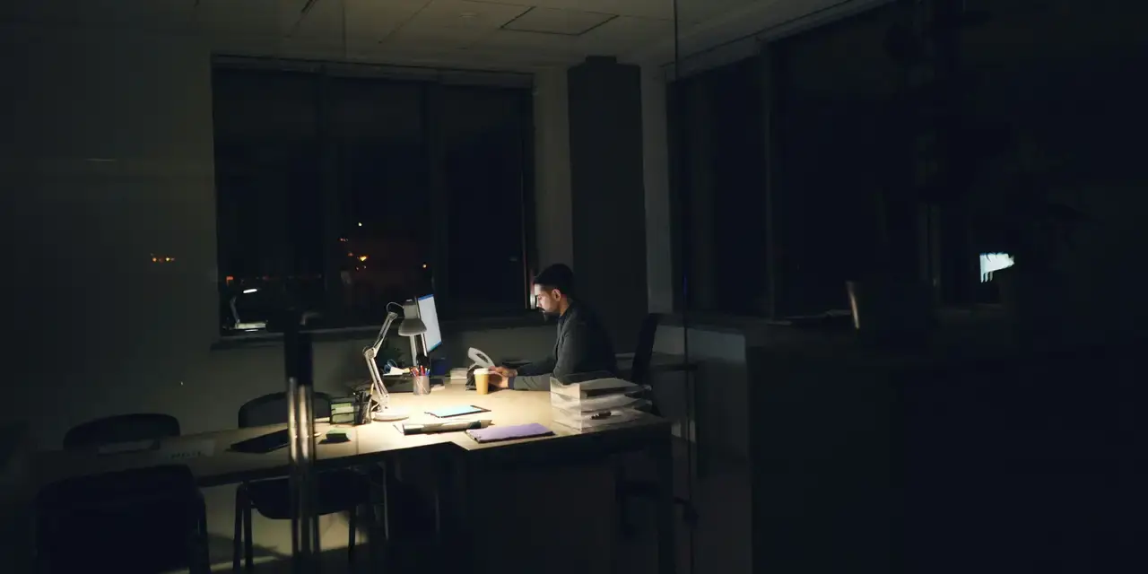 Persona trabajando de noche en un escritorio con luz tenue