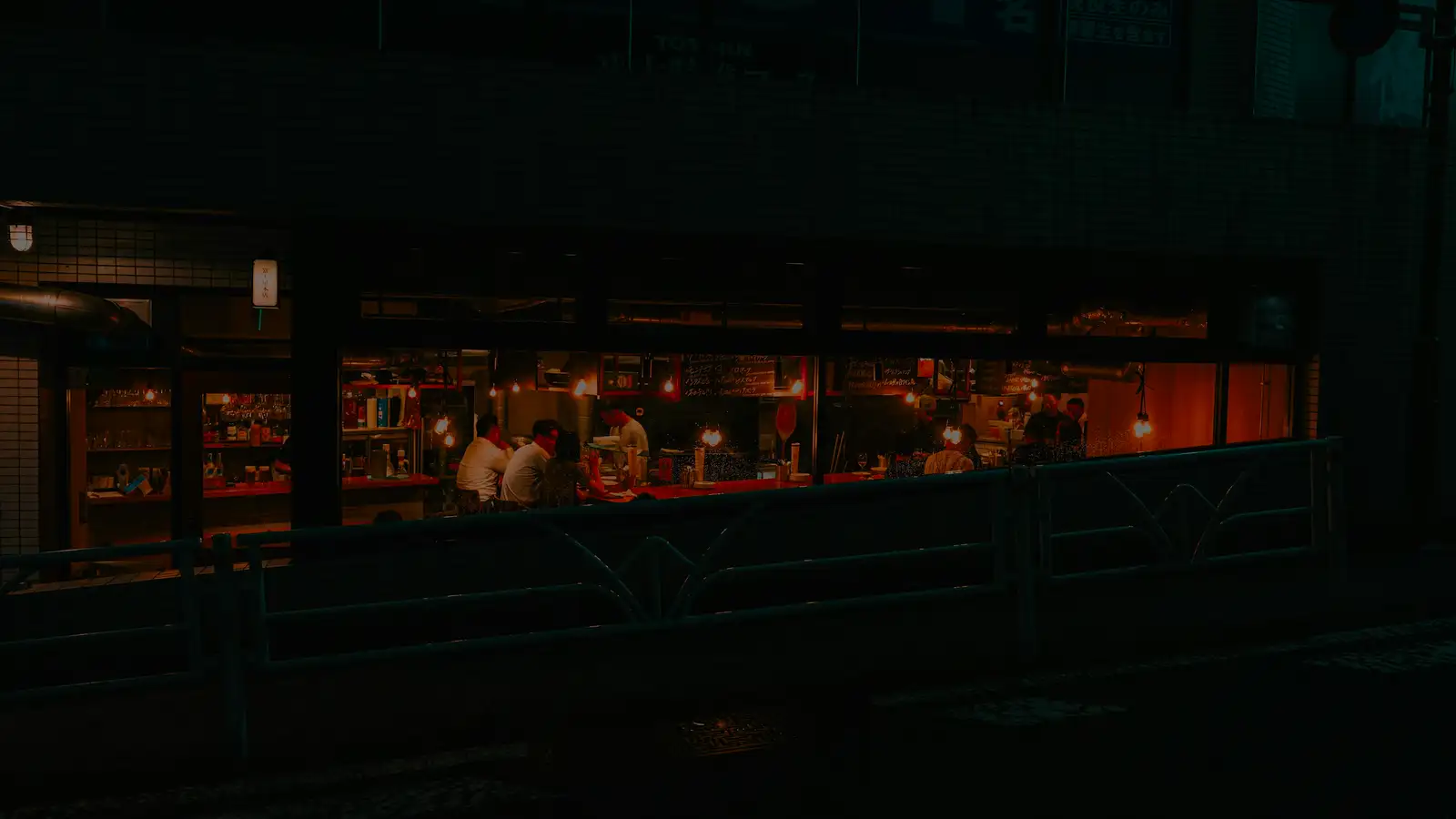 Interior iluminado de un restaurante visto desde la calle de noche
